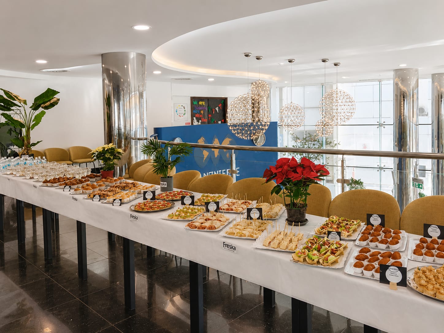 Long catering table of canapés and pastries set out for a corporate event