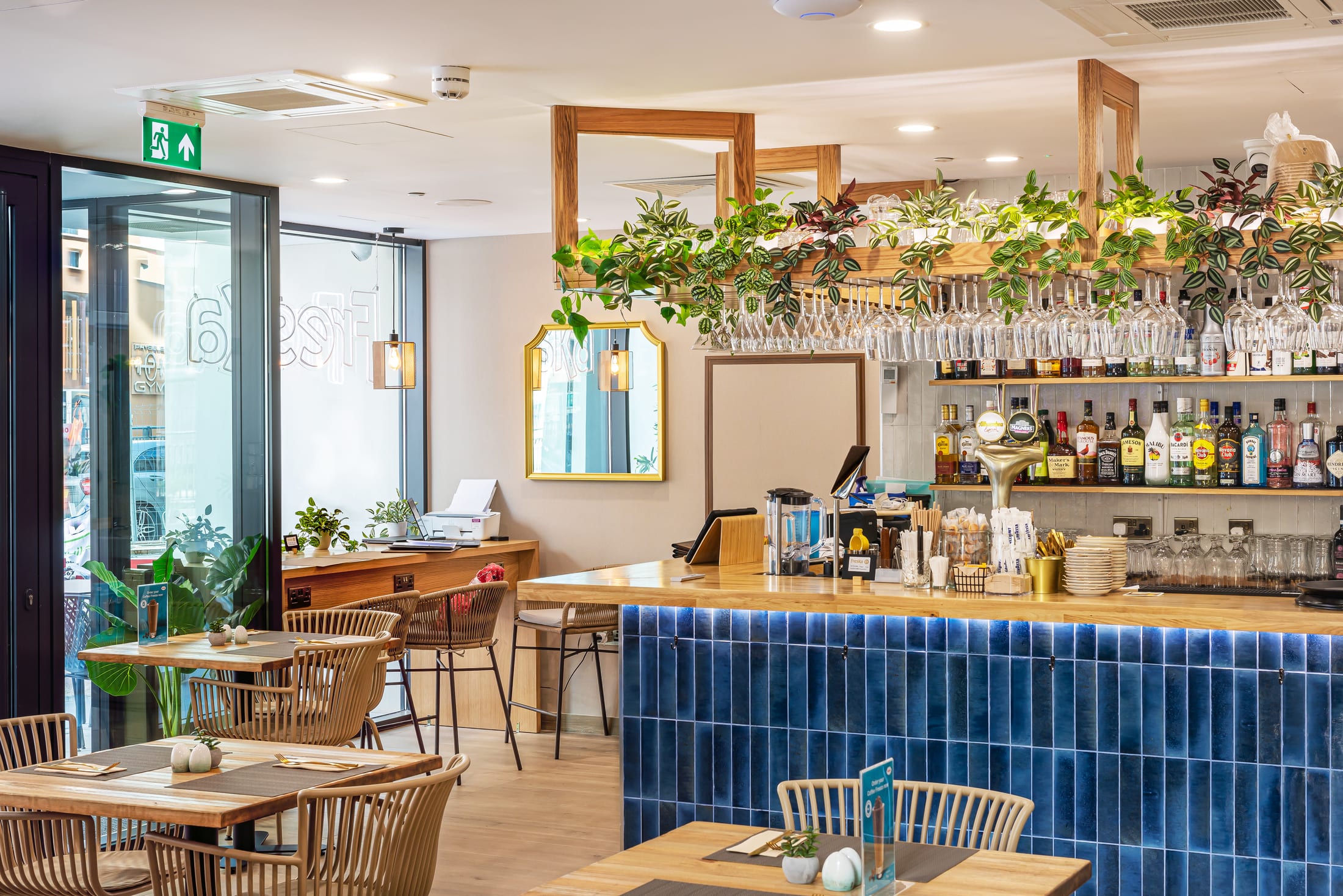 Freska E1 dining area with a wooden bar counter, blue tiled front and hanging plants