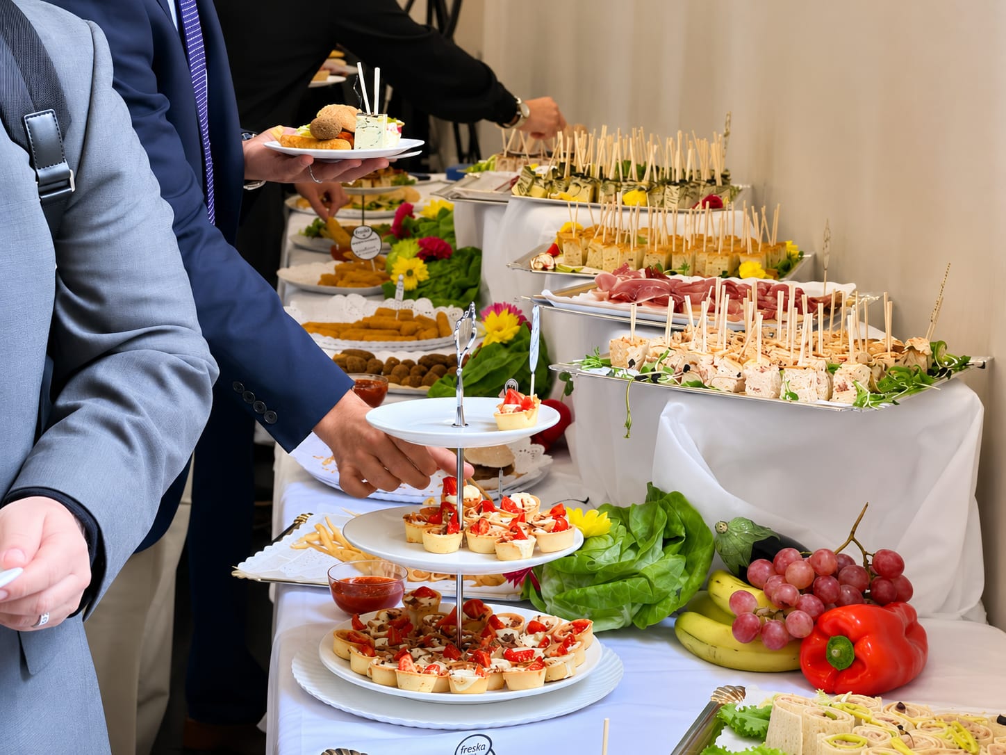 Guests helping themselves to a tiered catering stand of canapés at a Freska corporate event