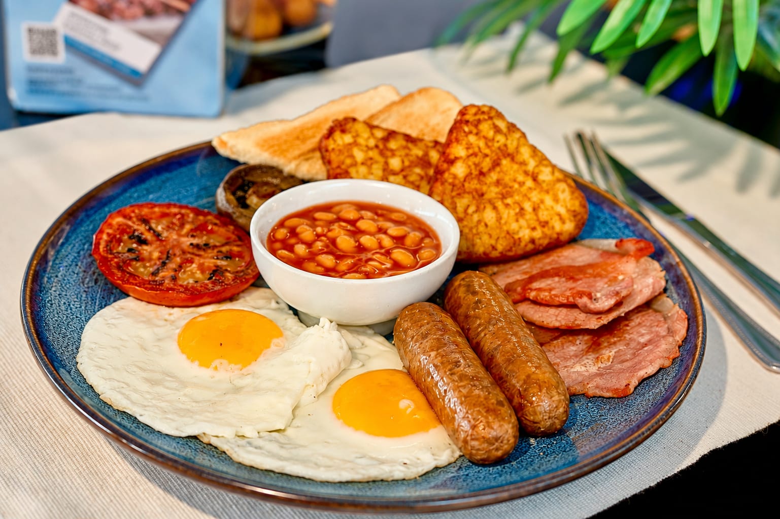 Full English breakfast with fried eggs, sausages, bacon, beans, hash browns and toast