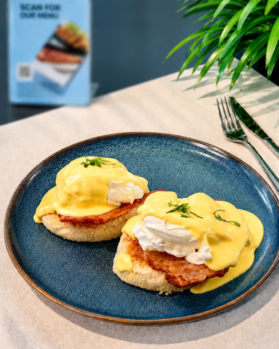 Two eggs Benedict muffins topped with poached egg, ham and hollandaise sauce
