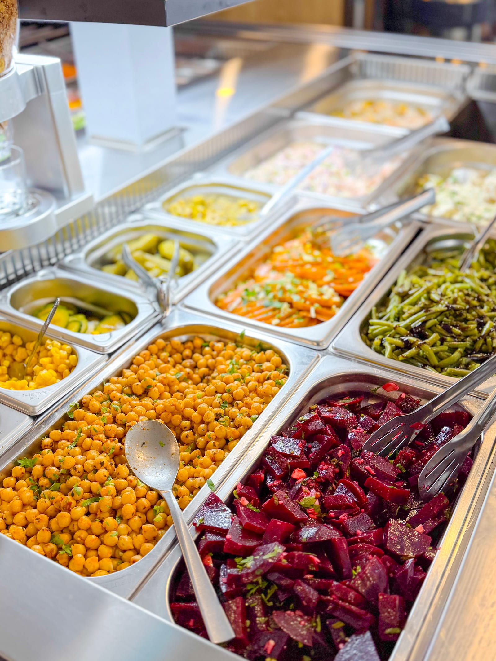Close-up of salad bar trays with lettuce, marinated peppers, peas and shredded carrot
