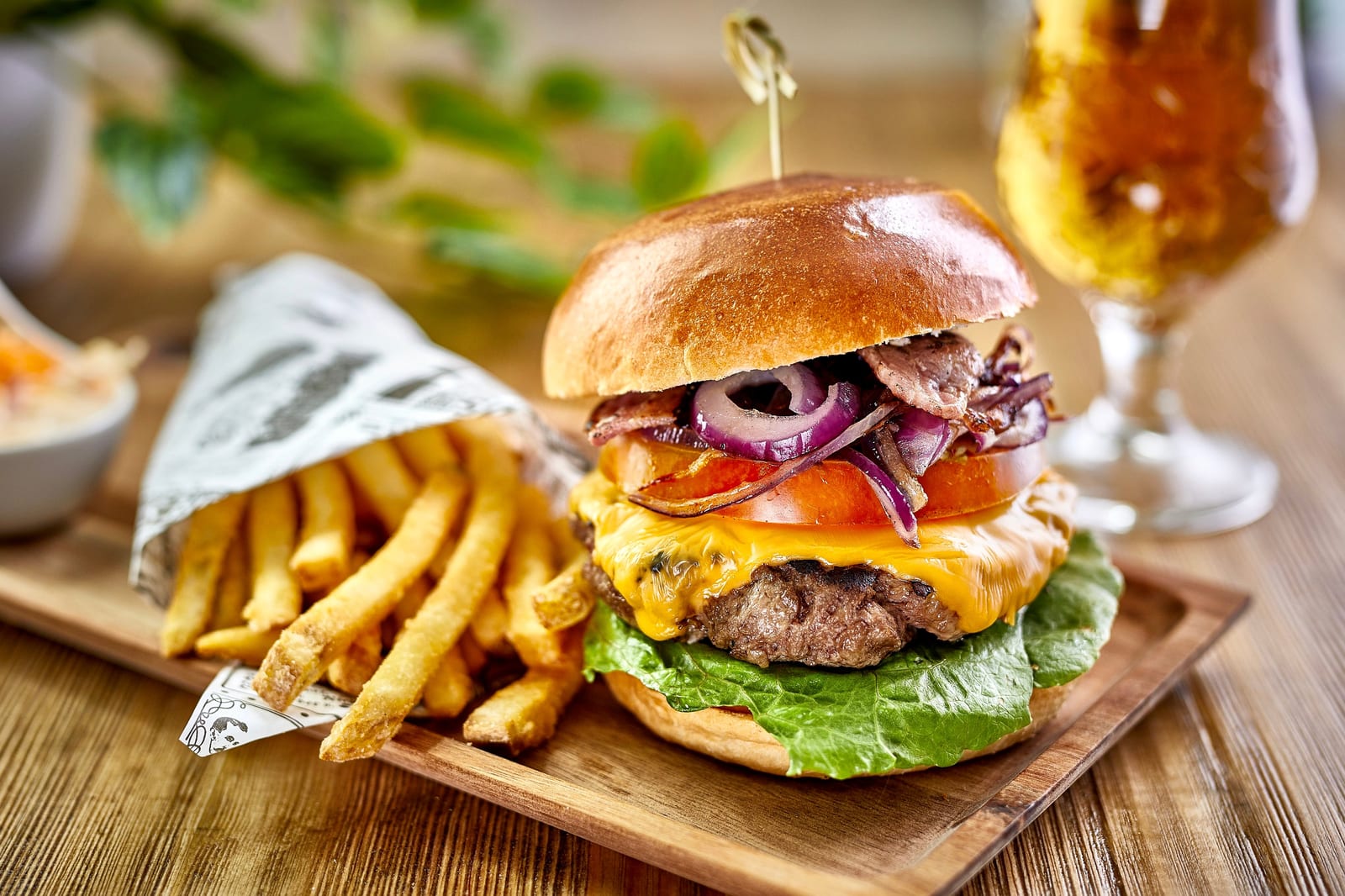Cheeseburger with red onion and tomato served with fries and a cold drink