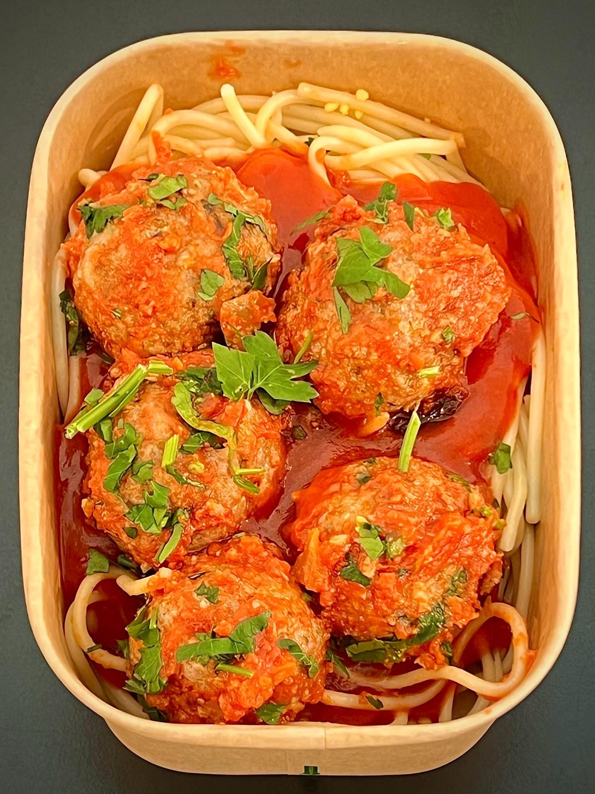Meal-prep box of meatballs in tomato sauce over spaghetti