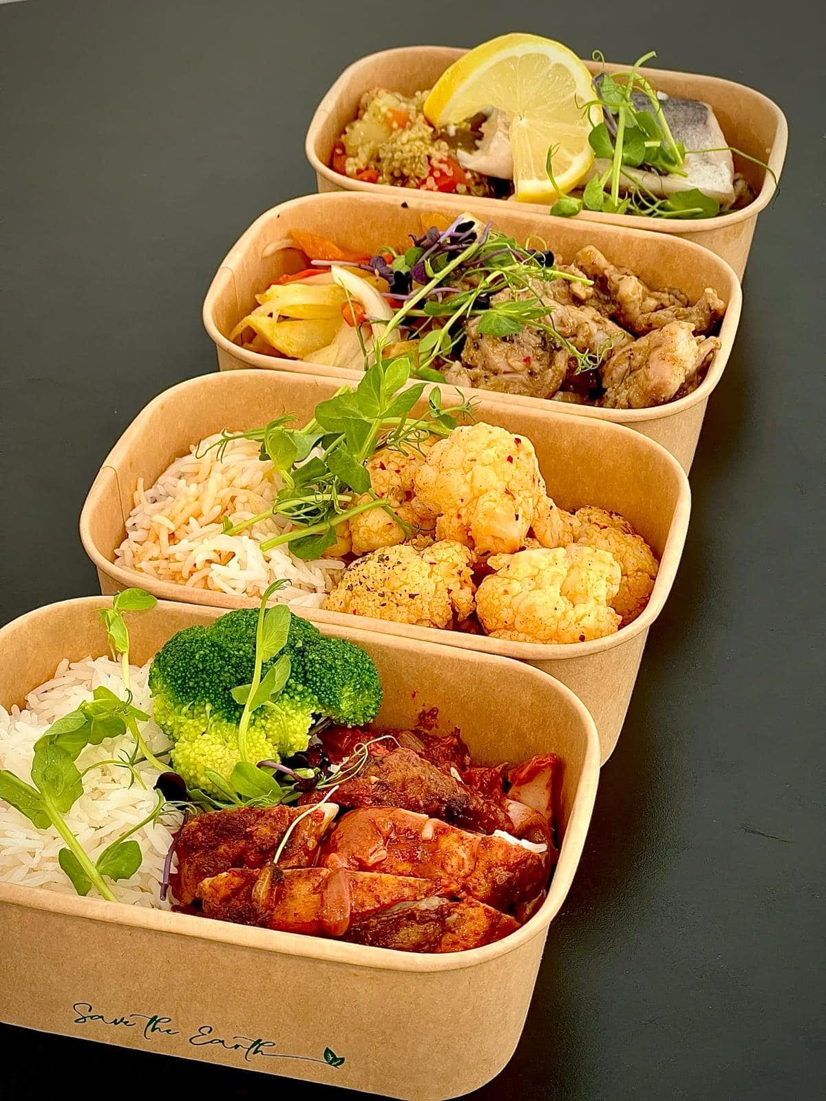 Four stacked meal-prep boxes with fish, chicken, cauliflower rice and beef stew
