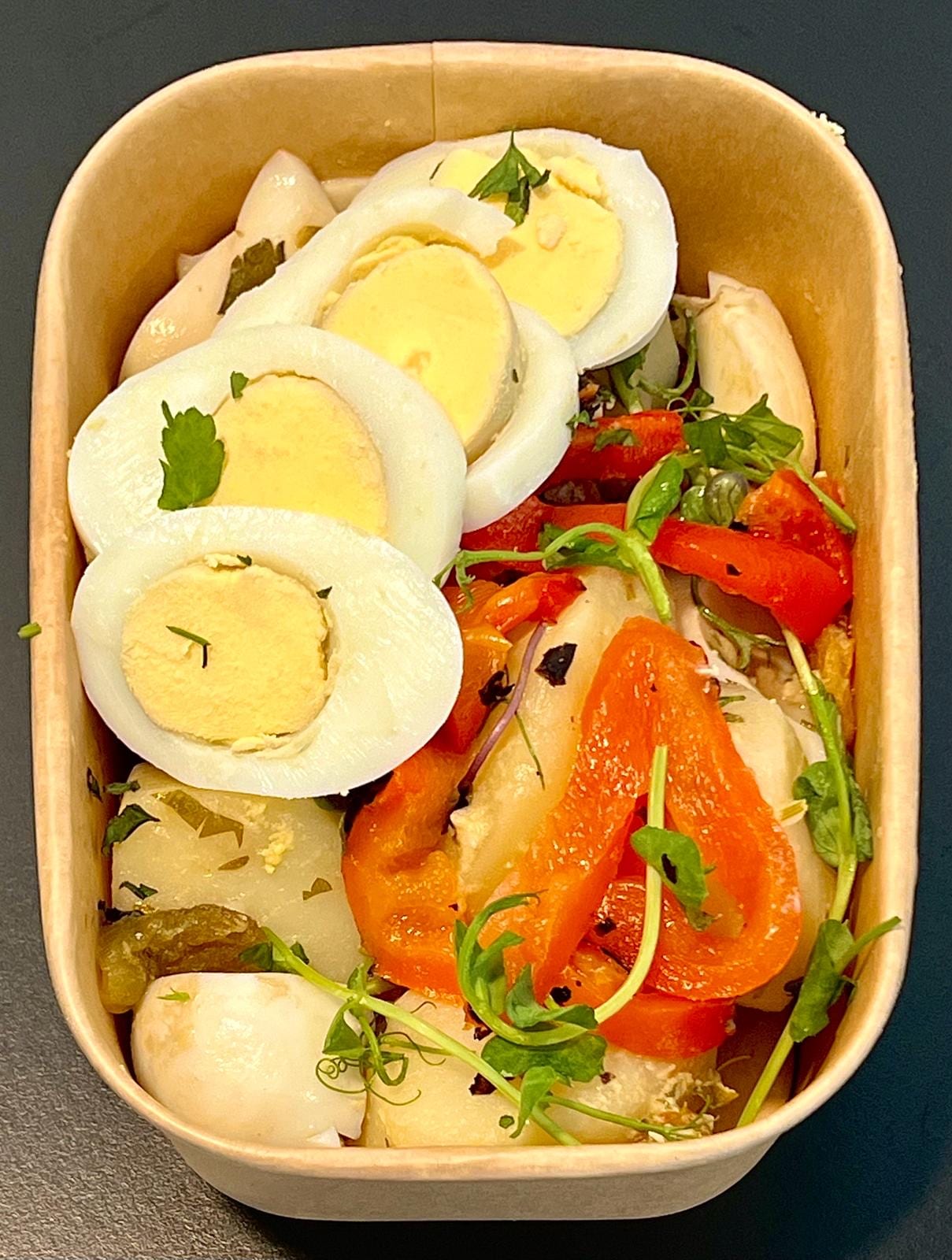 Meal-prep box of sliced boiled eggs, roasted peppers and potatoes