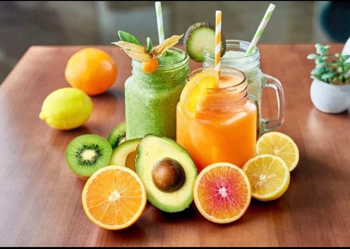 Fresh fruit smoothies in glass jars surrounded by citrus, kiwi and avocado