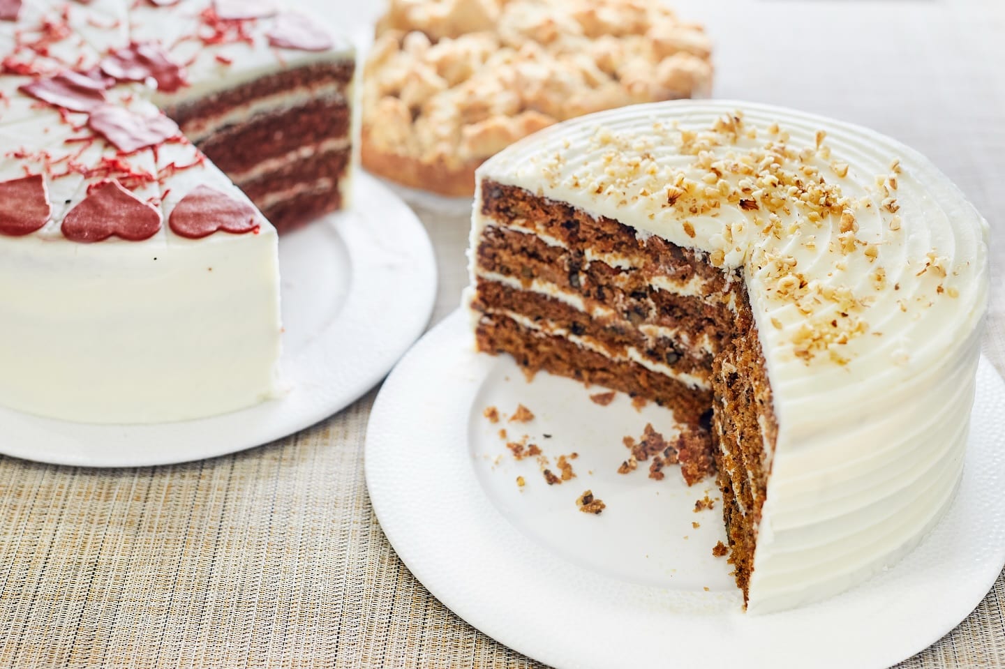 Slices of red velvet and carrot cake with cream cheese frosting on display
