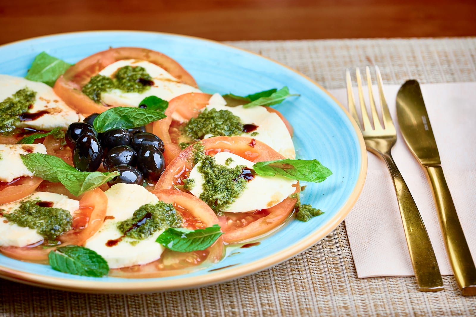 Tomato and mozzarella salad with black olives, pesto and mint