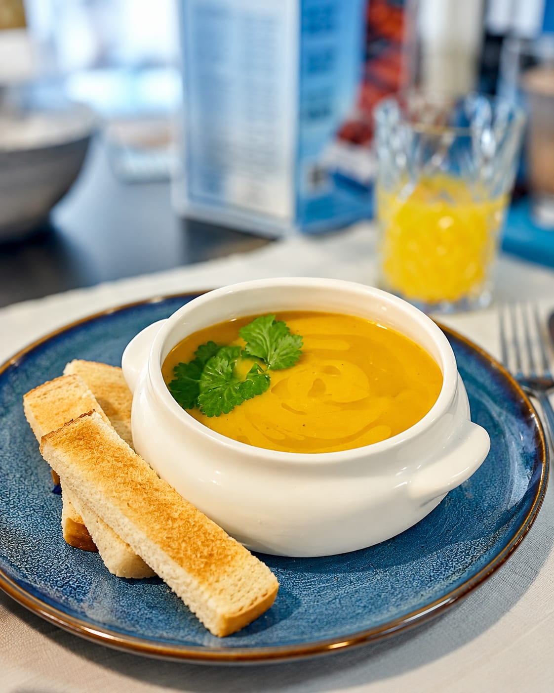 Bowl of pumpkin soup with fresh coriander and toasted bread fingers